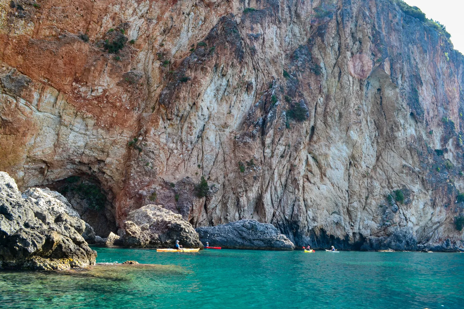 Paddling through rocky coastal formations near Parga, sea kayaking along the Ionian coastline in Epirus, Greece