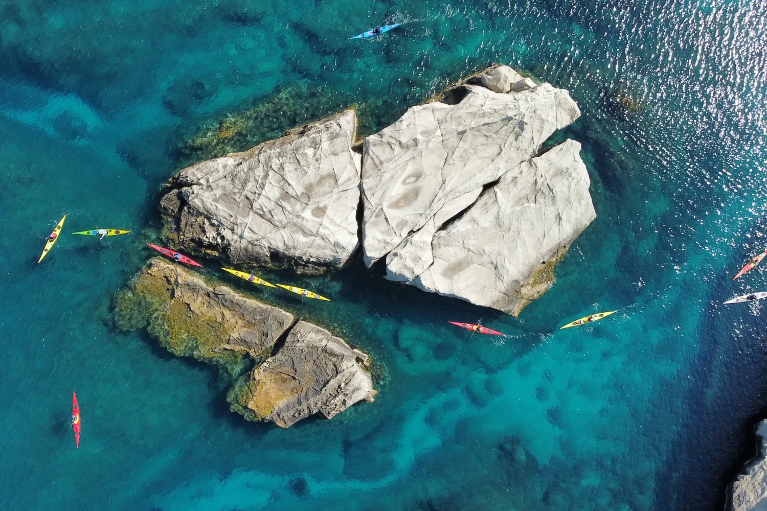 Aerial photo of Kayakers paddling along the volcanic coastline of Milos, Greece