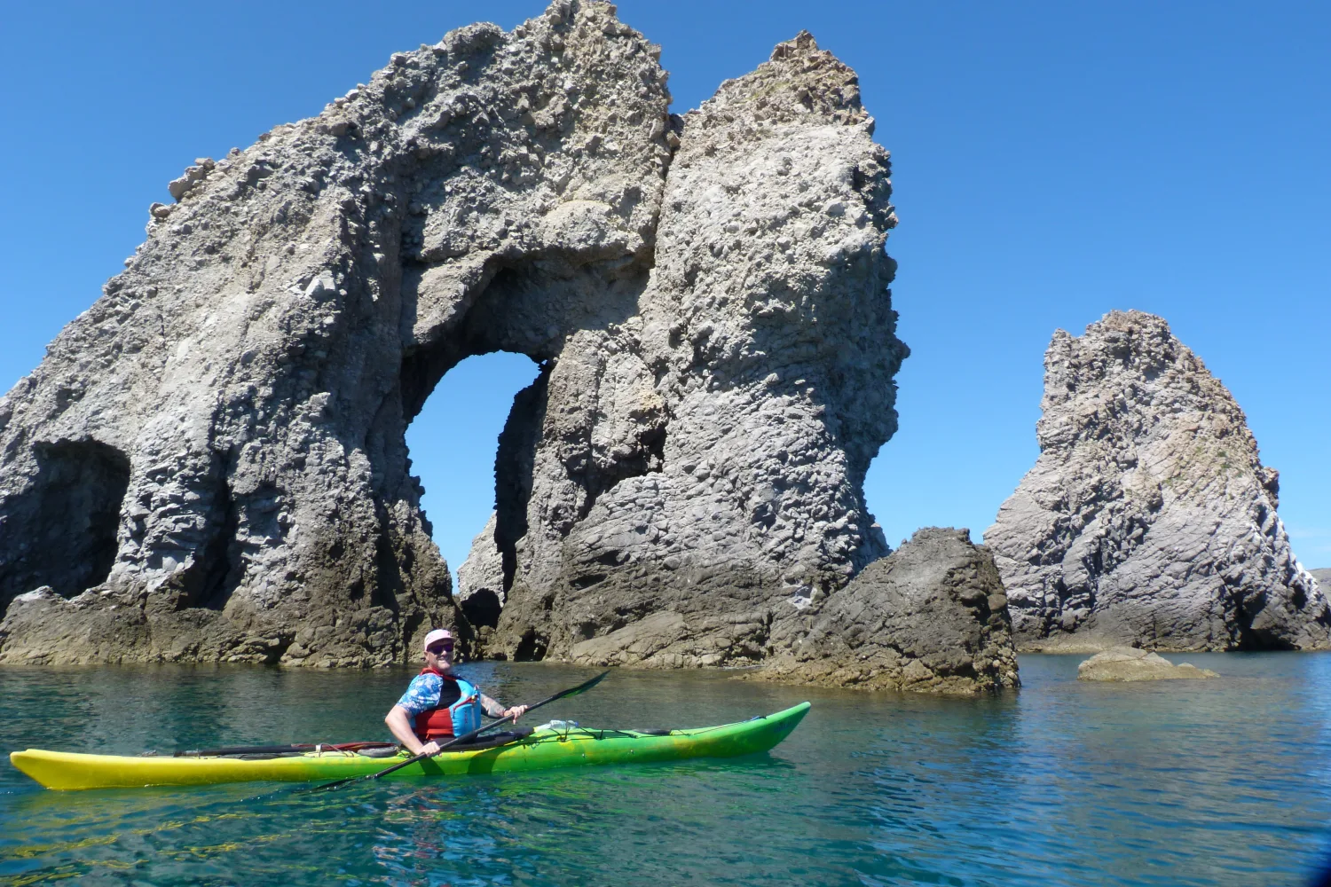Professional guide leading a sea kayaking tour around the coastal caves of Milos