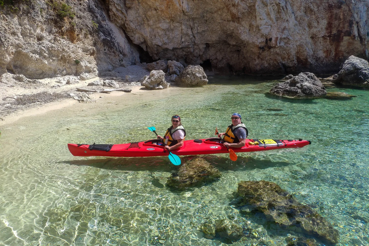 Couple sea kayaking along the coastline near Sivota in the Ionian Sea, enjoying a guided outdoor experience with Aegean Outdoors